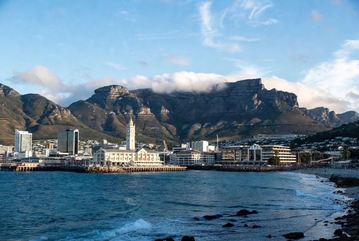Cape Town skyline with Table Mountain in background and modern waterfront buildings under clear blue sky